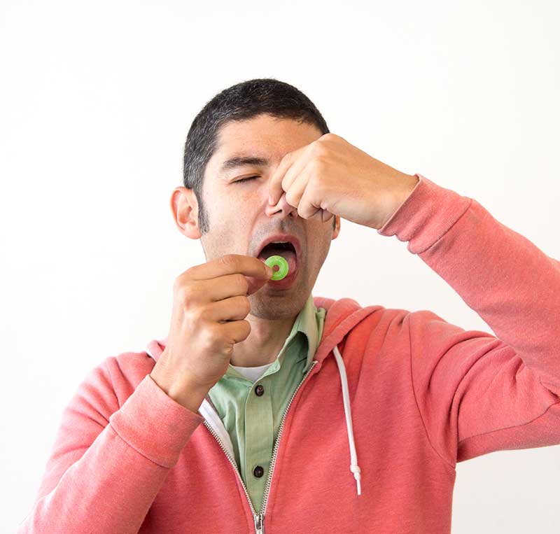 man holding his nose tasting a lifesaver
